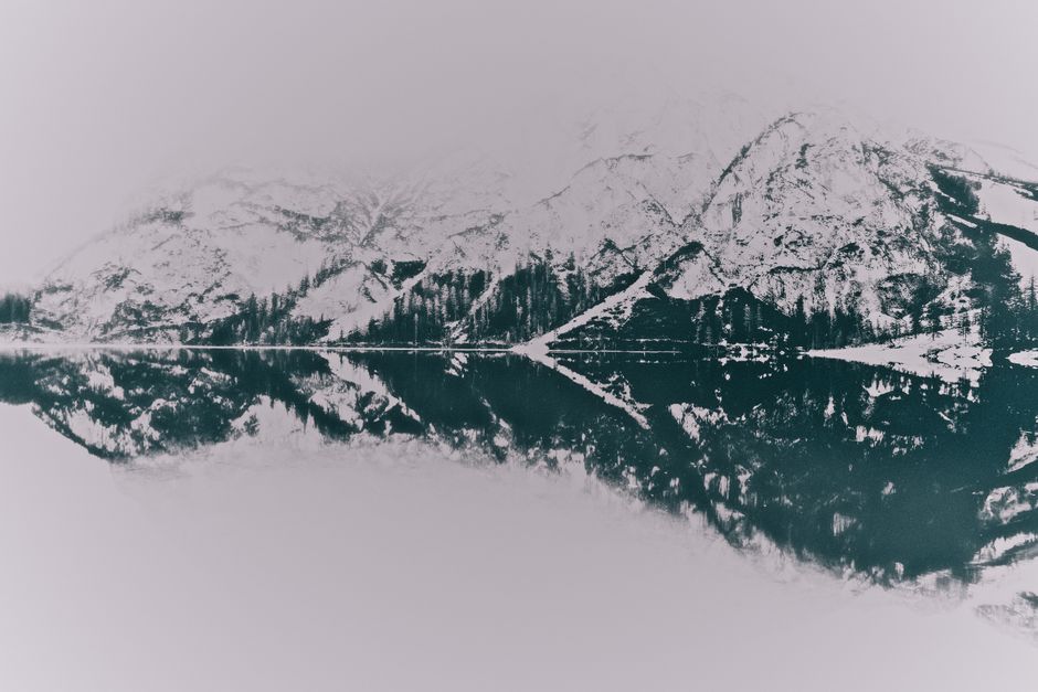 A tranquil winter scene of snowy mountains reflecting perfectly on a calm lake.